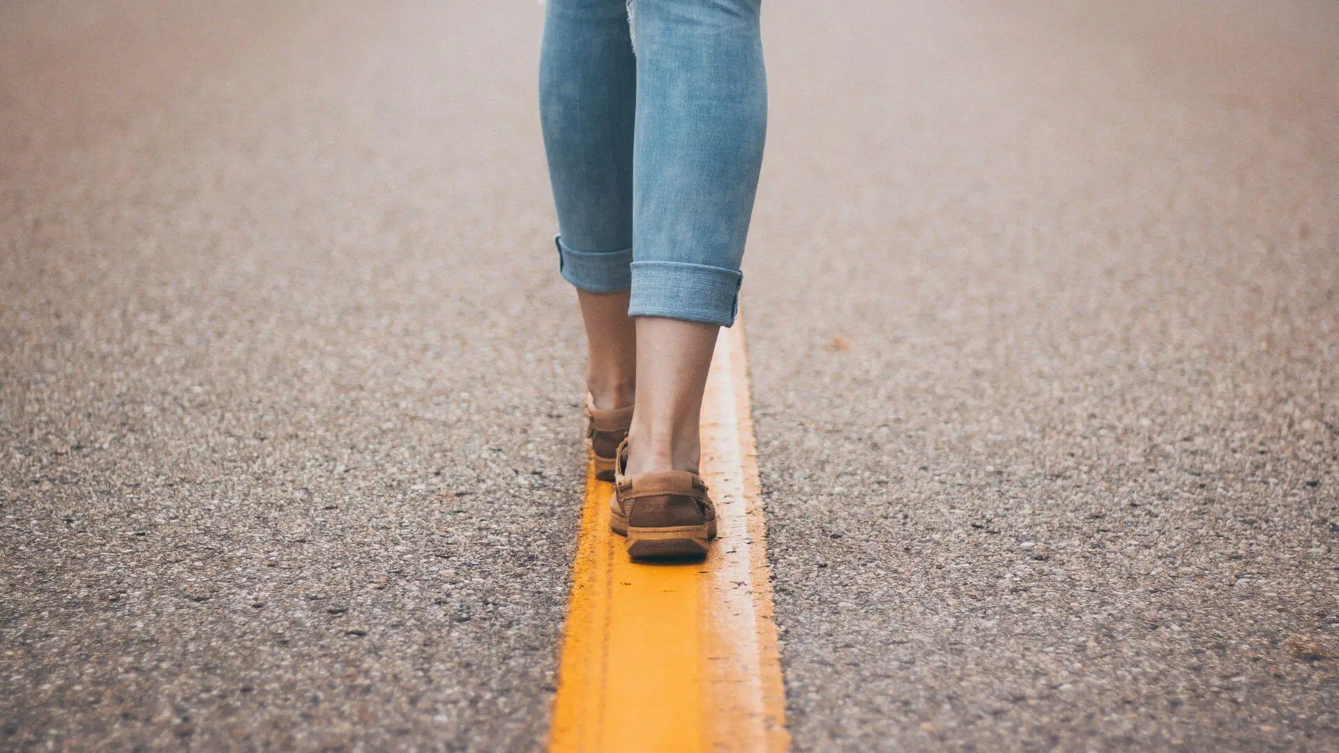 Uma mulher caminhando numa estrada.